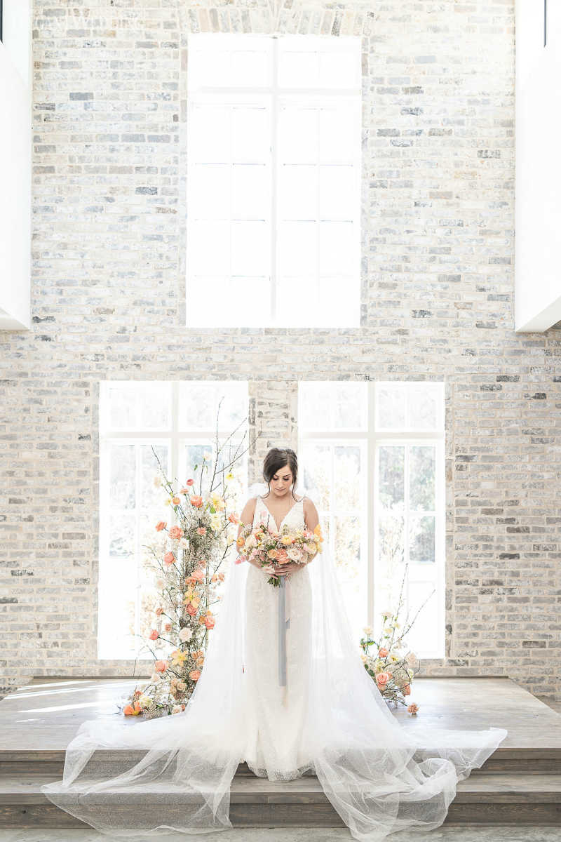 bride standing at the ceremony with peach flowers